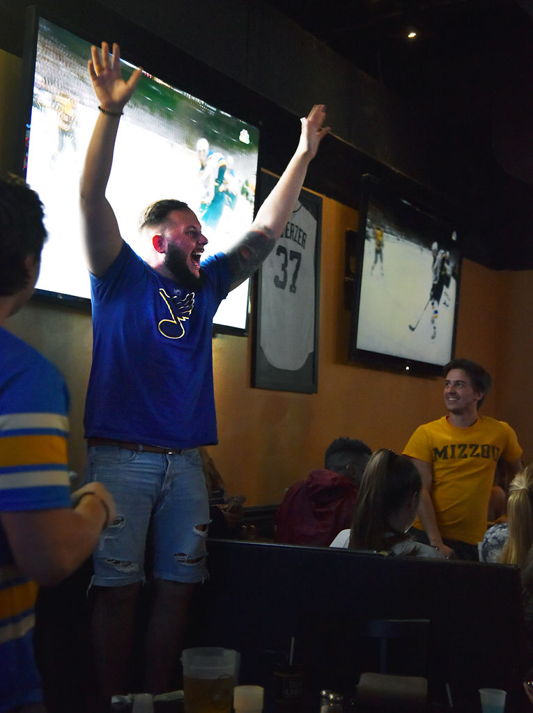 Tyler Evola throws his hands in the air from atop a chair when the Blues scored a goal in the third period